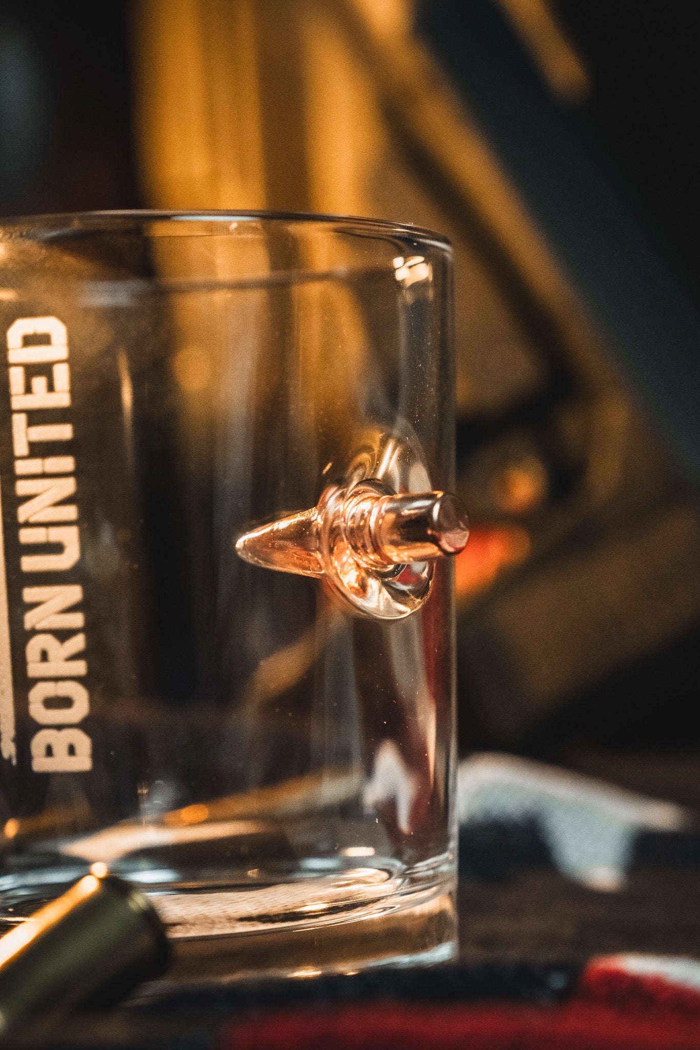 The Born United Bullet Whiskey Glass by Born United Private Label features a real bullet embedded in the side and "BORN UNITED" printed vertically, making it a distinctive and memorable addition to any bar collection.