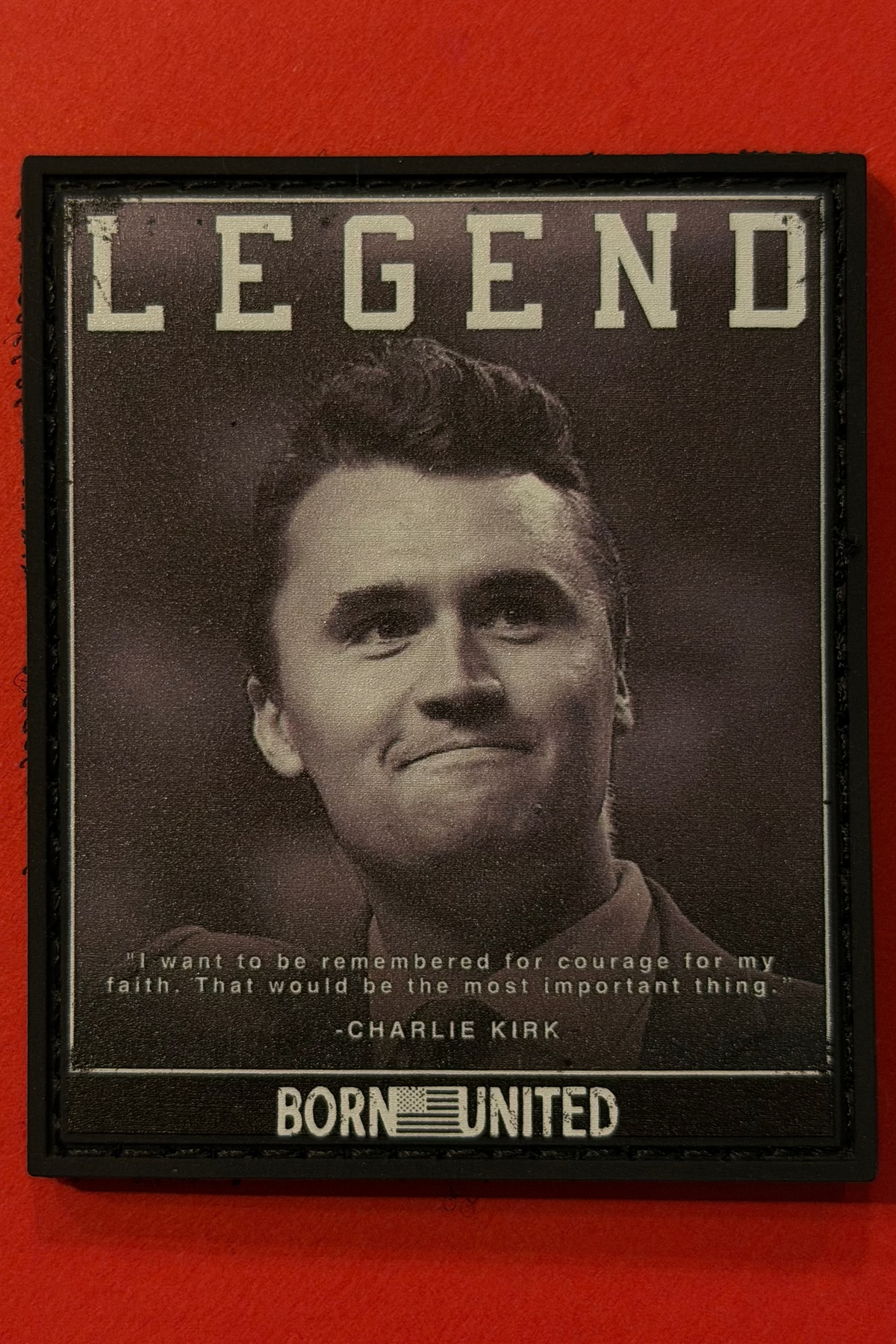 A black and white photo of a man with "LEGEND" above, featuring a quote from Charlie Kirk: "I want to be remembered for courage, for my faith. That would be the most important thing." Product: Legend - Charlie Kirk PVC Patch by Born United Private Label.