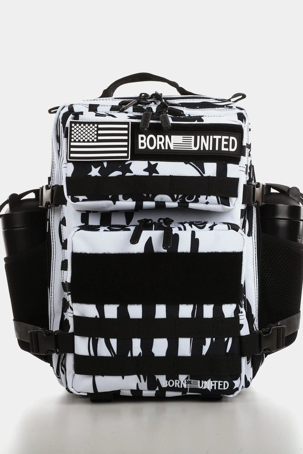 The American Stealth Special Edition Tac-Pac - 25L by Born United Private Label is a black and white backpack with an abstract pattern, flag patches, and BORN UNITED text. It features multiple compartments, side pockets, utility straps, and adjustable padded shoulder straps.