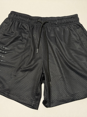 The 13th Men's Mesh Lifestyle Shorts | 5.5" - Forgiven, featuring an elastic waistband, black drawstring, and side pockets, are classic unisex black shorts designed for all-day comfort and style—shown here laid flat on a light surface.
