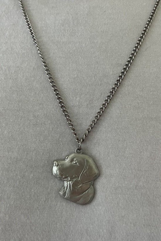 The Good Ol Boy stainless steel necklace by Mucker Bucket features a silver chain and a dog head pendant with detailed facial features and fur texture, displayed on a plain light gray background.