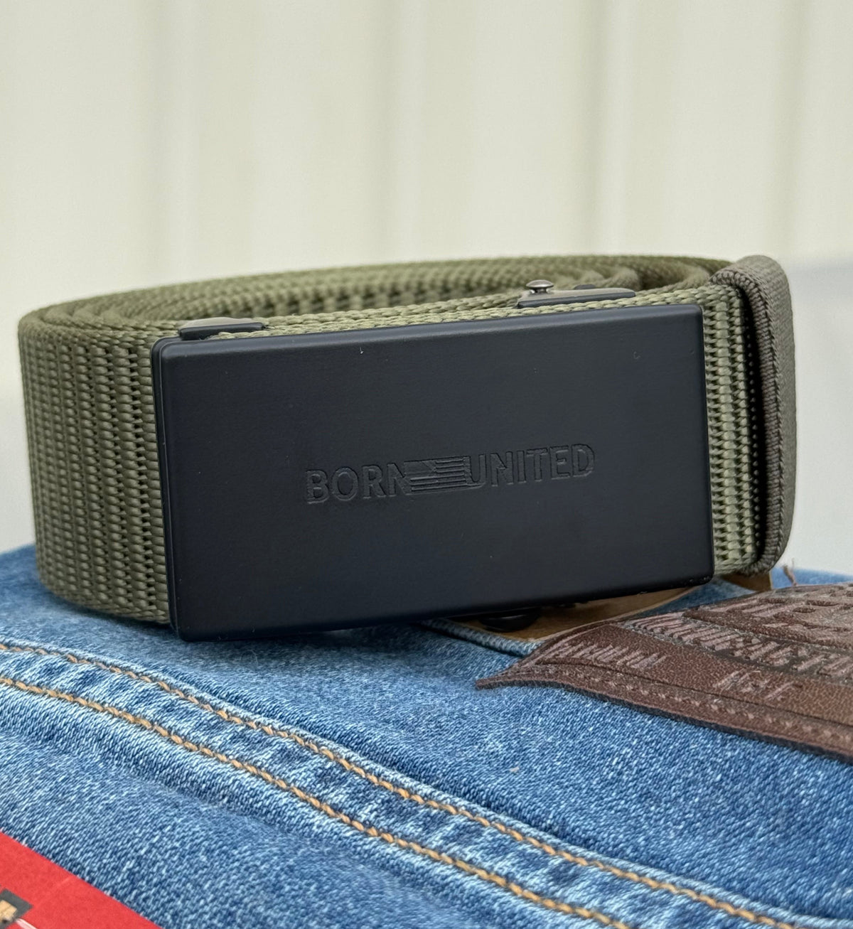 Green ratchet belt on a pair of denim jeans
