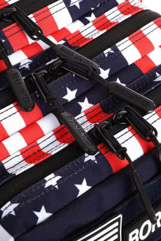 Special Edition close-up of the Ultimate Patriot Special Edition Tac-Pac - 25L by Born United Private Label, featuring a design reminiscent of the American flag with red, white, and blue stars and stripes. Black zipper pulls are visible, each labeled distinctively.