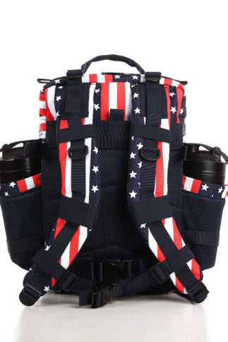 The Ultimate Patriot Special Edition Tac-Pac - 25L from Born United Private Label showcases an American flag design with red and white stripes, white stars on blue, plus multiple compartments and side pockets featuring black zippers.