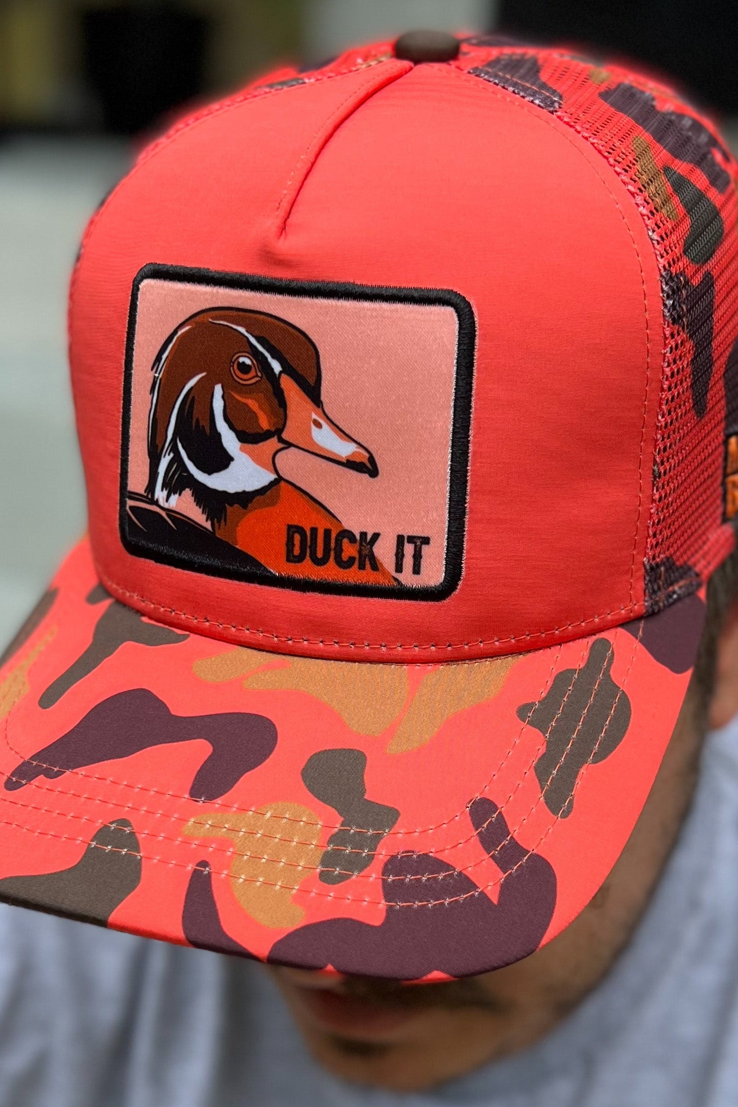 mucker bucket - "duck it" orange camo trucker hat on model