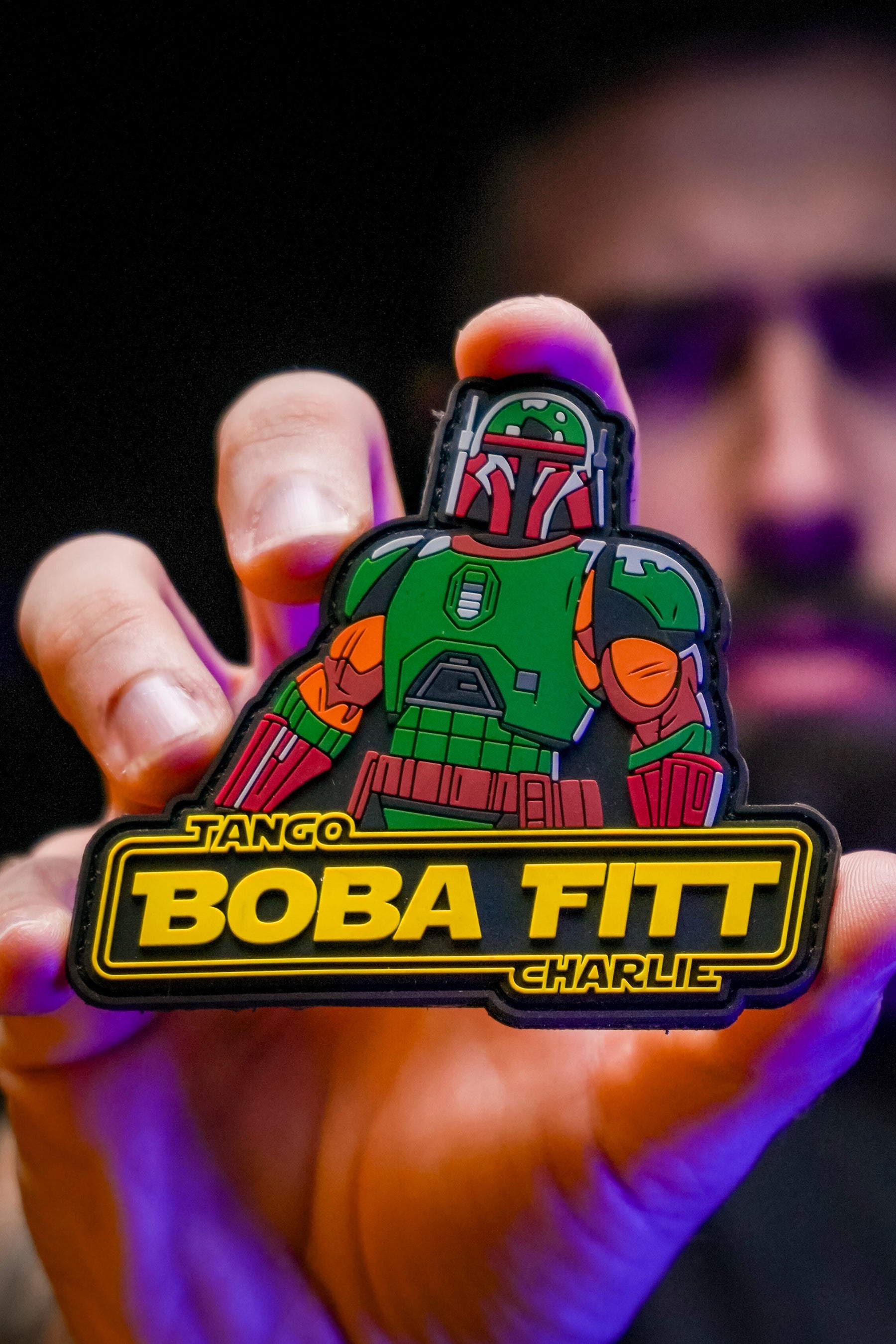 Hand holding a 'Tango Boba Fett Charlie' patch with a dark background
