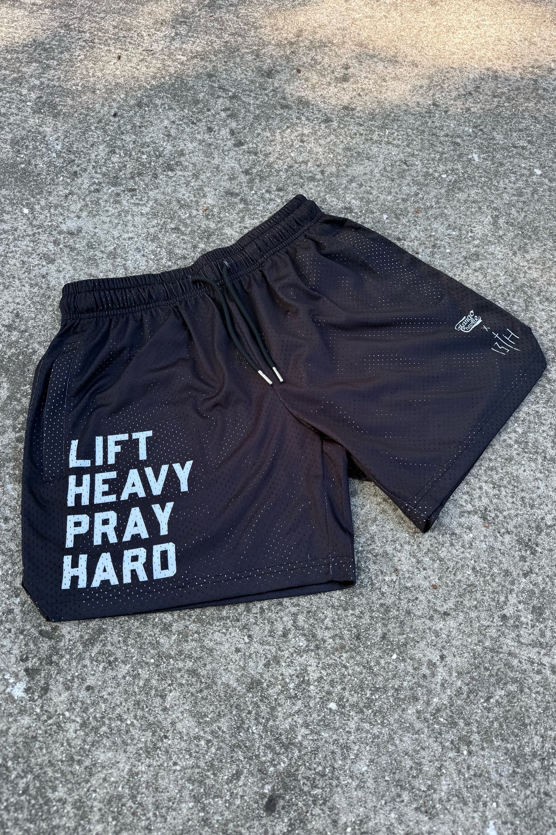 Tango Charlie Apparel’s Men's Mesh Lifestyle Shorts | 5.5" - Lift Heavy Pray Hard Black feature bold white "LIFT HEAVY PRAY HARD" text on the left leg—ideal gym shorts for any active lifestyle.