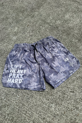 The Men's Mesh Lifestyle Shorts | 5.5" - Lift Heavy Pray Hard Deadwood by Tango Charlie Apparel feature gray camo with white text and graphics on the right leg—perfect for the gym or your active lifestyle.