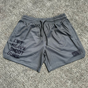 Men's Mesh Lifestyle Shorts | 5.5"- LHSG OD Green by Tango Charlie Apparel feature bold LIFT HEAVY. SHOOT GUNS. text on the left leg, a small BANG UNITED logo on the right, black drawstrings, and classic comfort for everyday performance.