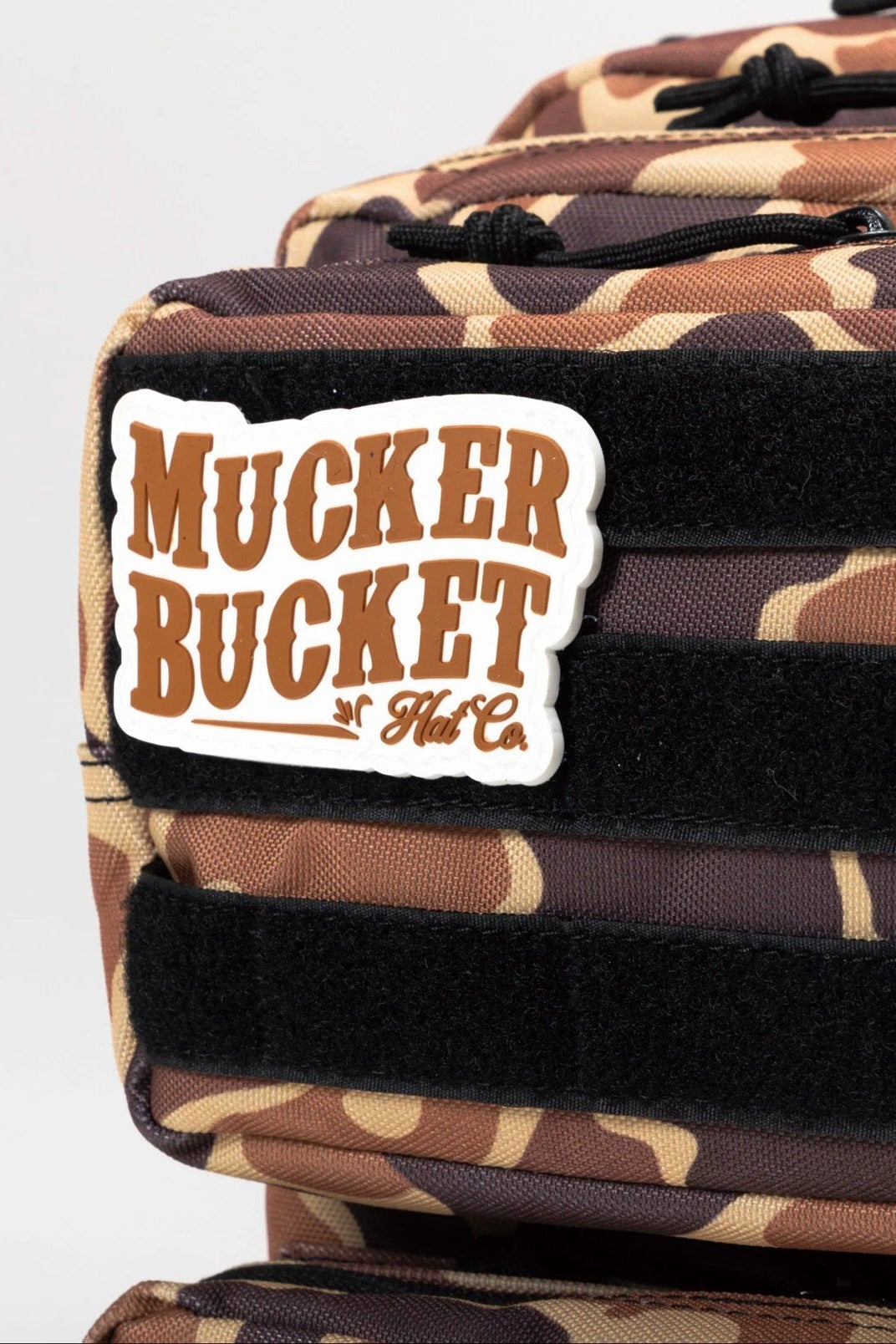 Close-up of the Mucker Bucket Duck It Limited Edition Tac-Pac 25L hunting backpack with black straps and a branded patch, perfect for your next adventure.