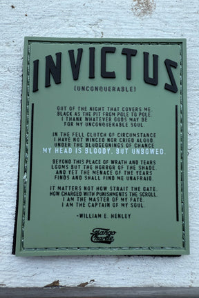 An image features the Invictus PVC Patch by Tango Charlie Apparel on a white wooden surface, displaying William E. Henleys poem Invictus. The title Invictus (Unconquerable) is prominently in large letters at the top, with feet partially visible at the bottom.