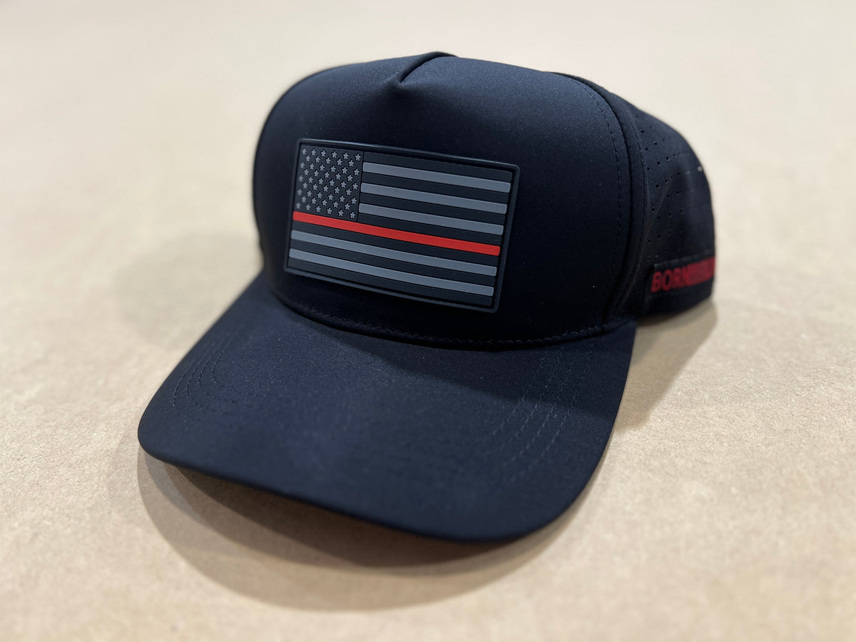 The Born United Premium Flag Snapback - TRL by Born United Private Label is a black cap with a grayscale American flag and a bold red stripe, symbolizing firefighter support. Displayed on a neutral, light-colored surface.