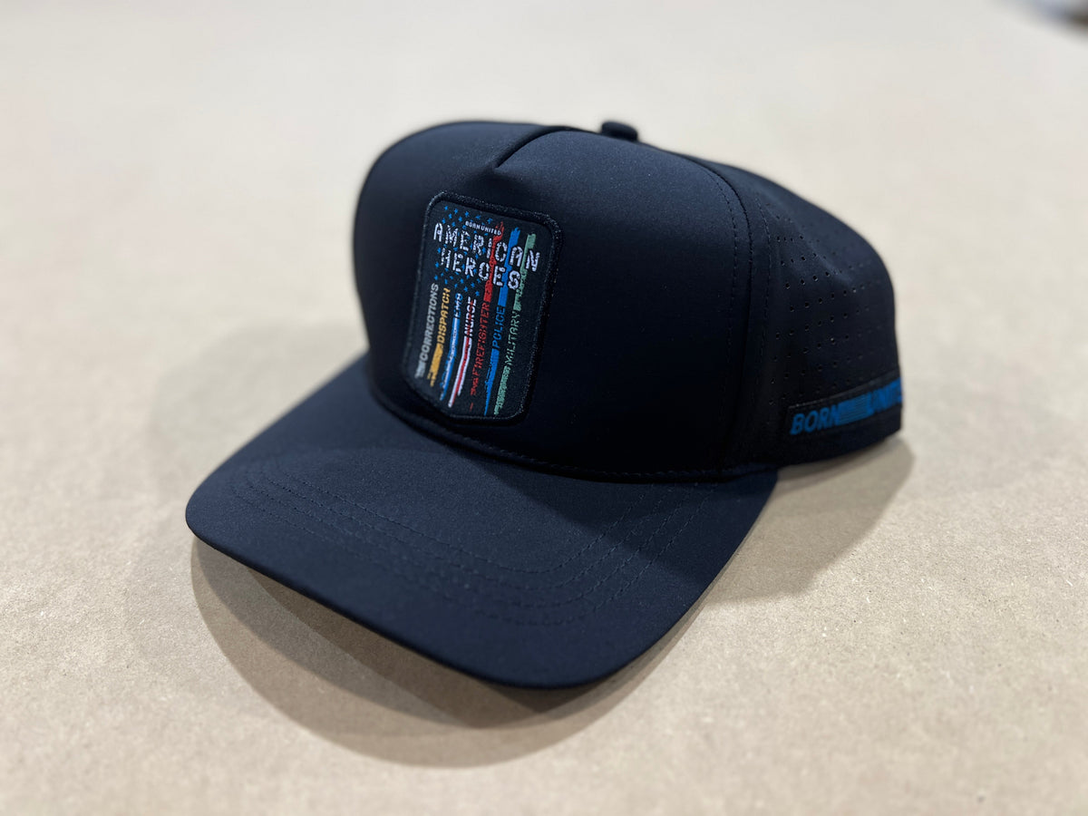 The Born United Premium Snapback - American Heroes by Born United Private Label is a black cap featuring an "AMERICAN HEROES" patch over colorful vertical lines, with "BORN THERE" text on the side, set against a neutral background.