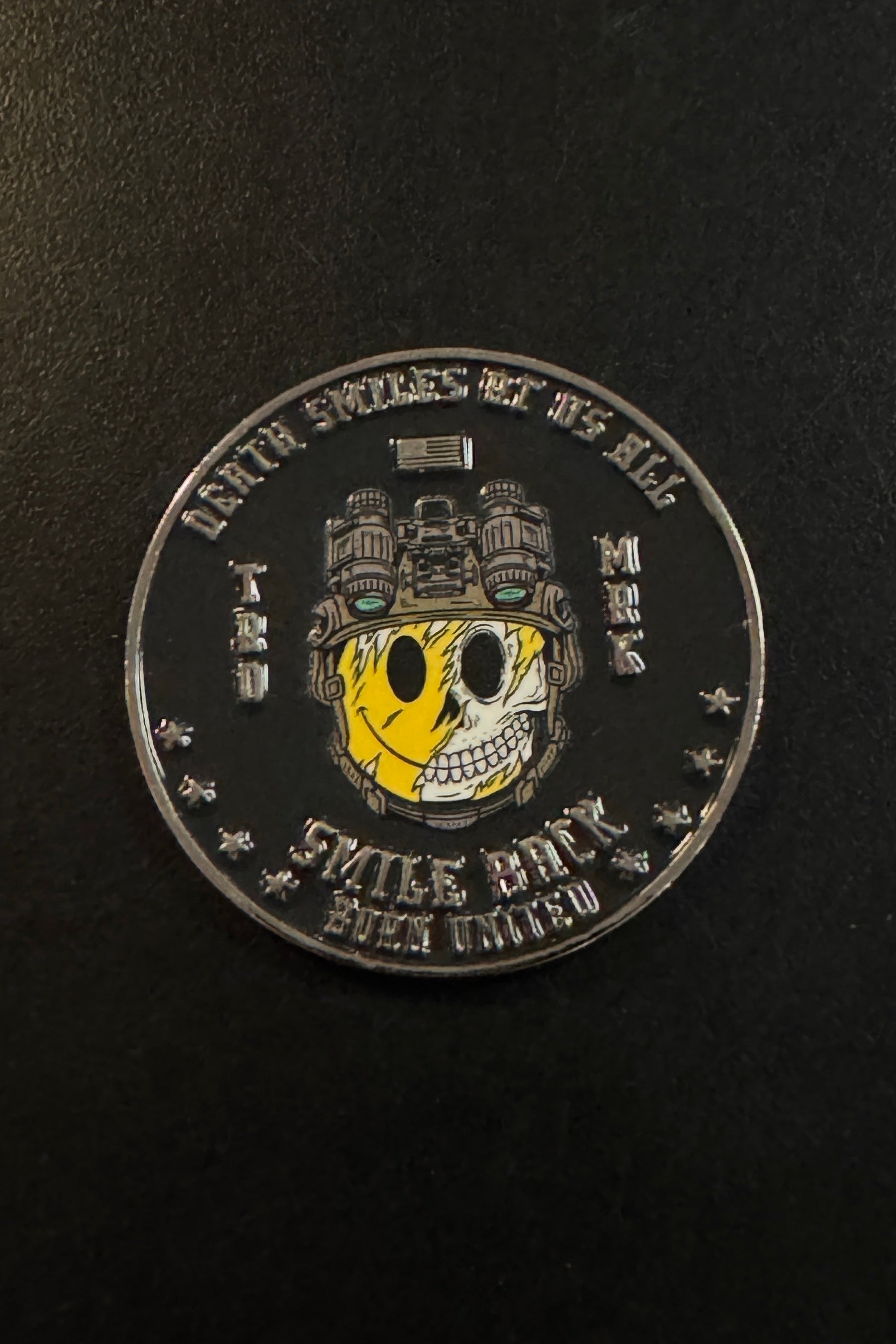 The Smile Back Challenge Coin from Born United Private Label features a round design with a half-smiling, half-skeletal face in a helmet, encircled by the inscription “DEATH SMILES AT US ALL, STYLE BOY, EVEN UNITED”—plus a subtle reminder to Smile Back.