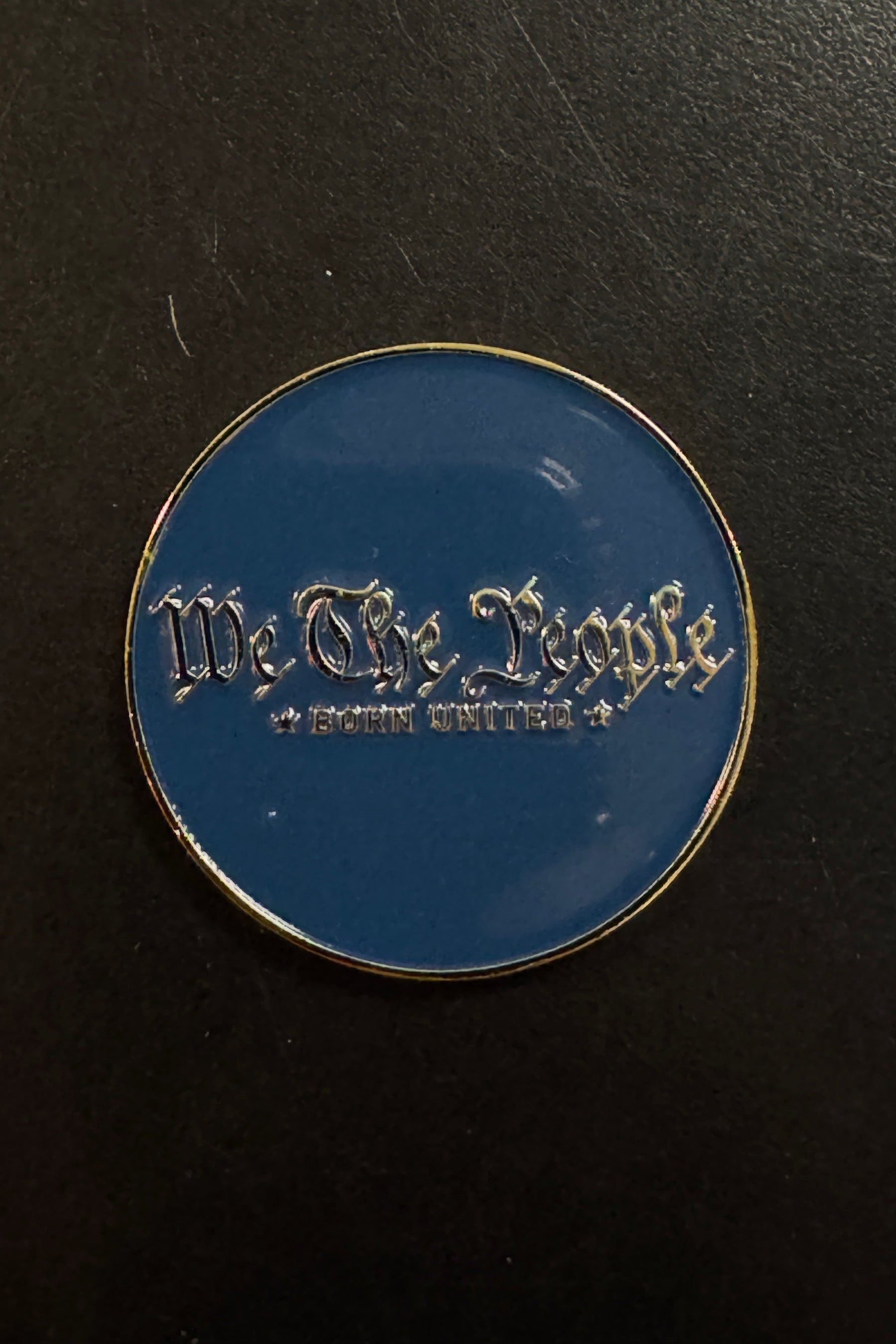 Certainly! Here’s a rewritten sentence using the provided product data: The Born United Private Label “We The People Challenge Coin” features a round blue design with gold trim and showcases the words “We The People” and “Born United” in silver gothic-style lettering, evoking the look of a classic challenge coin.