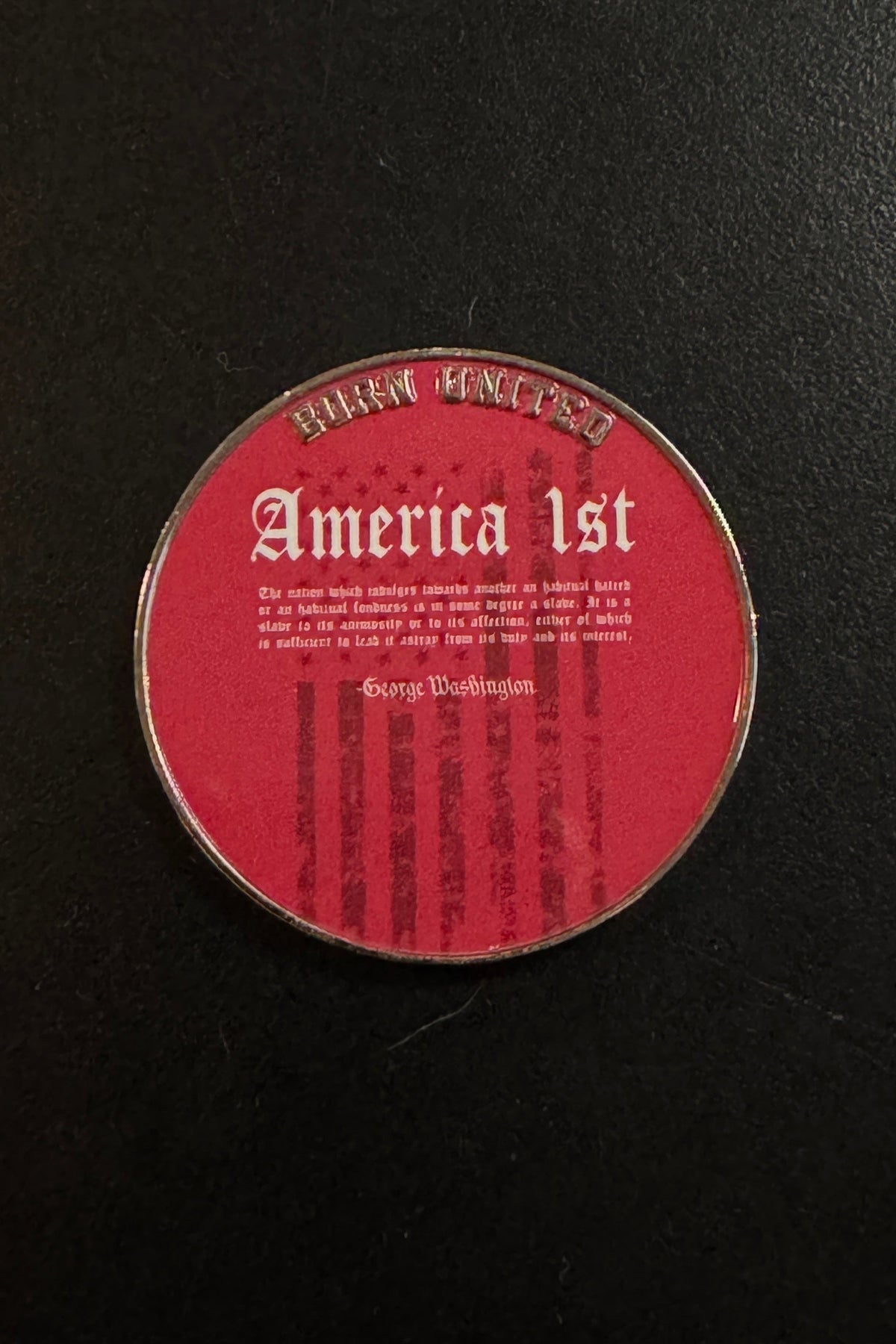 A round America First Challenge Coin by Born United Private Label features a red background with “America 1st” inscribed on it and a quote attributed to George Washington, set against faint American flag stripes.