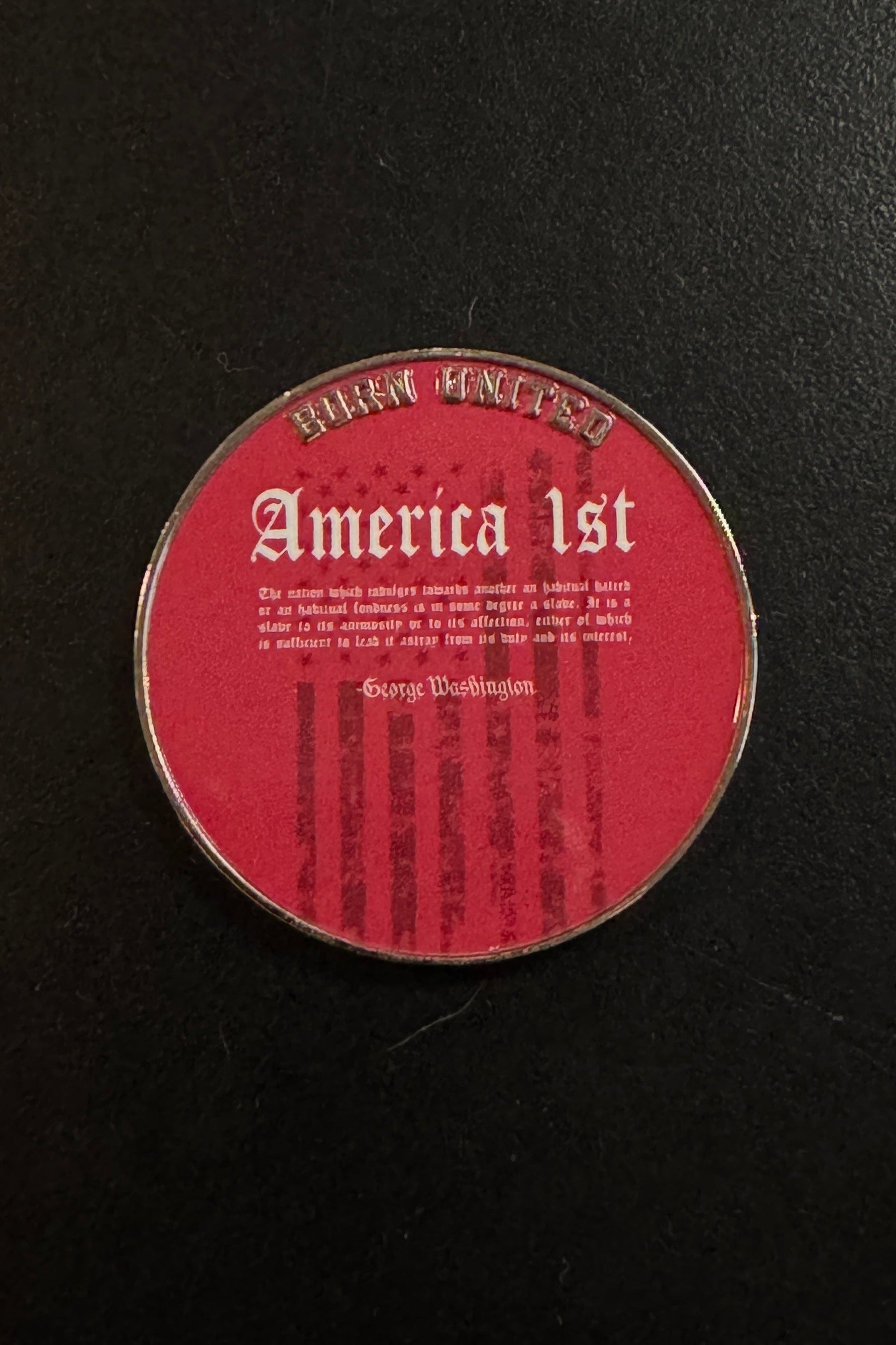 A round America First Challenge Coin by Born United Private Label features a red background with “America 1st” inscribed on it and a quote attributed to George Washington, set against faint American flag stripes.