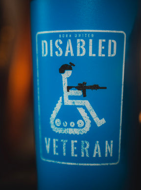 A blue sign features a wheelchair with tank tracks and a person holding a rifle, labeled “Born United Disabled Veteran”—a powerful design for the 20oz Disabled Veteran Tumbler from Born United Private Label.