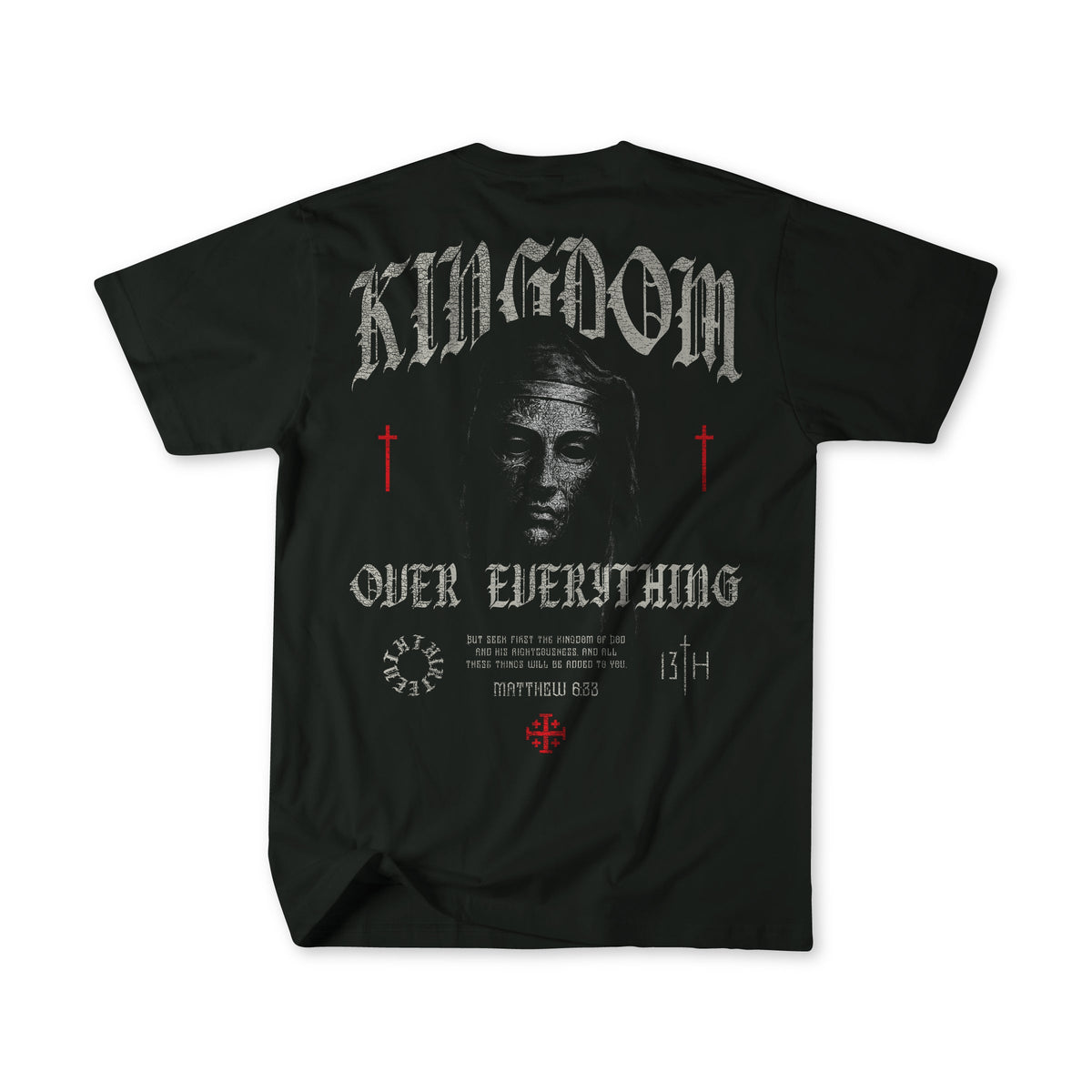 The 13th Kingdom Over Everything Premium Tee features a grayscale Jesus face, "KINGDOM OVER EVERYTHING" text, red crosses, Matthew 6:33 in gothic font on the back, and decorative accents.