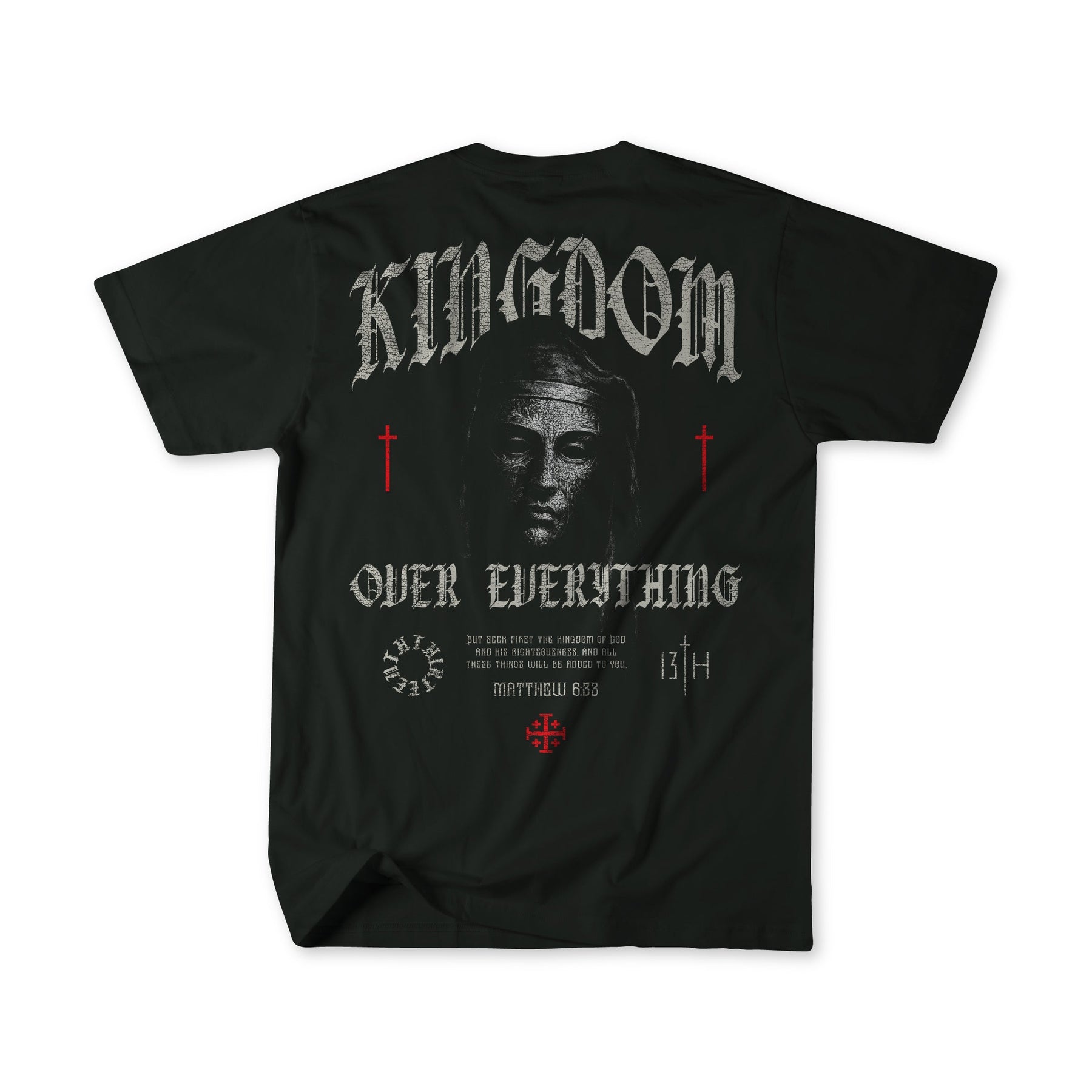 The 13th Kingdom Over Everything Premium Tee features a grayscale Jesus face, "KINGDOM OVER EVERYTHING" text, red crosses, Matthew 6:33 in gothic font on the back, and decorative accents.
