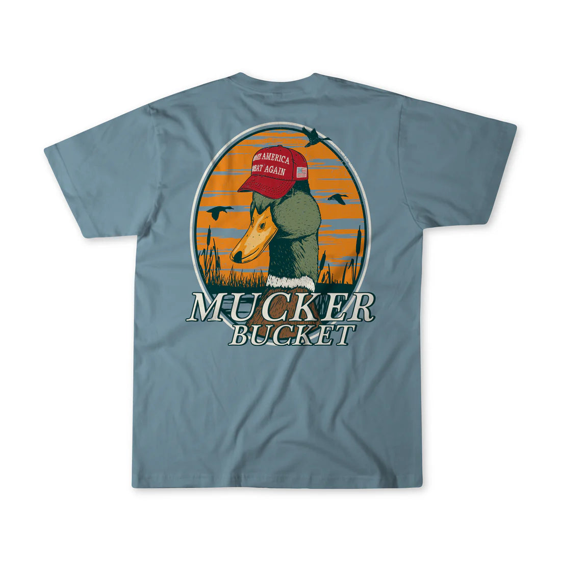 Experience the charm of Mucker Buckets Smart Duck Tee, a garment-dyed gem featuring a duck in a red cap with Make America Quack Again text amidst a sunset and cattails. Crafted from 100% ring-spun cotton, this premium relaxed fit tee showcases MUCKER BUCKET on muted blue-gray.