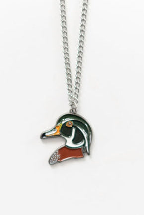 The Mucker Bucket Wood Duck Necklace features a ducks head pendant in vibrant green, orange, and white on a simple stainless steel chain with a white backdrop. Made in the USA, it exudes elegance and charm.