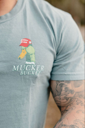 Light blue t-shirt with 'Mucker Bucket' logo worn by a person with tattoos.