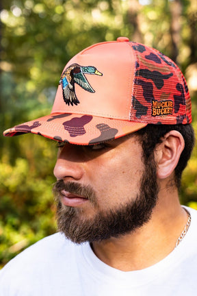 Man wearing a pink and black cap with a duck design outdoors