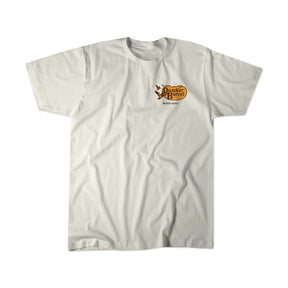 The Quacker Barrel Premium Tee by Mucker Bucket is a plain white, relaxed fit shirt with a small brown and yellow “Old Country Store” logo on the upper left chest.