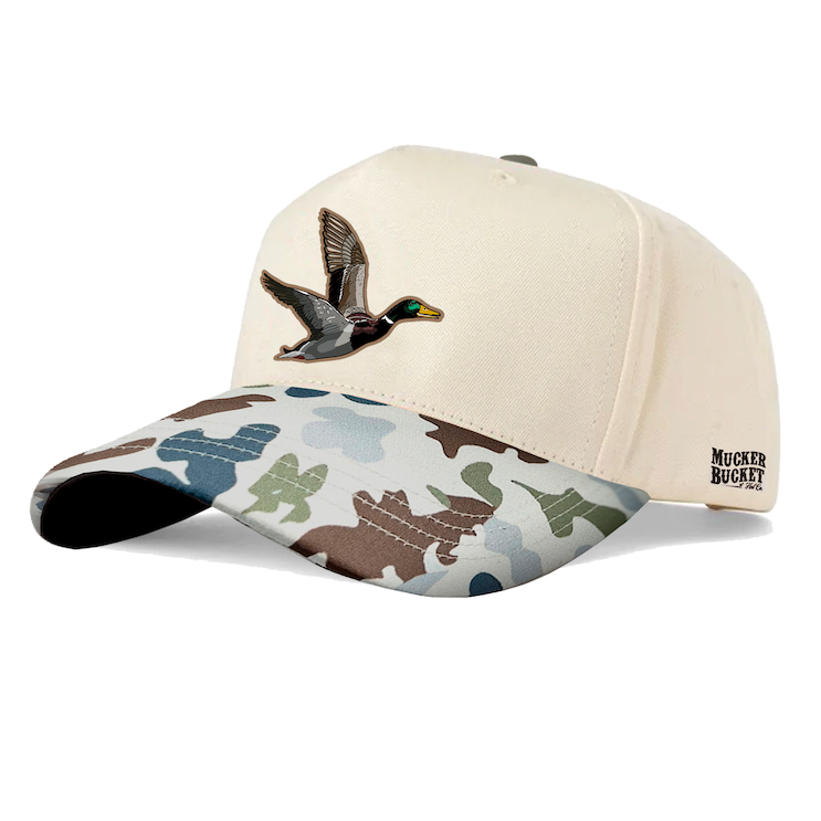 The Mucker Bucket Camo Duck Bucket Curved Brim is a cream-colored snapback hat with detailed duck embroidery on the front patch, a camo brim, and Mucker Bucket text displayed on the side.