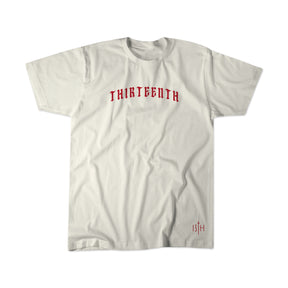 The Serpent's And Doves Premium Tee by 13th is a plain white shirt with "THIRTEENTH" in bold red gothic letters across the chest, inspired by Matthew 10:16, and a small red 13th logo near the bottom hem.