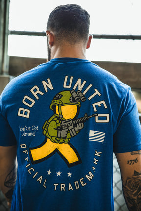 A man wears a blue "You've Got Ammo!" T-shirt by Born United Private Label, featuring a cartoon soldier with rifle on the back, "BORN UNITED OFFICIAL TRADEMARK," plus stars, flag, and a retro tech twist on AOL's "You've Got Mail.