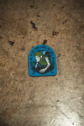 A rugged PVC patch by Born United Private Label shows a skeleton with seaweed and helmet, gripping a trident, plus the text: “Bury me in the shallows, but I’ll return. Born united. TRD. BNM.” Product: The Shallows PVC Patch.