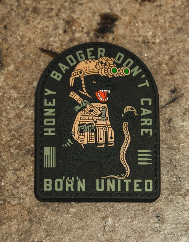 The Honey Badgerin PVC Patch by Born United Private Label features an armored honey badger in night vision goggles and tactical gear holding a snake, with HONEY BADGER DONT CARE above and BORN UNITED below.