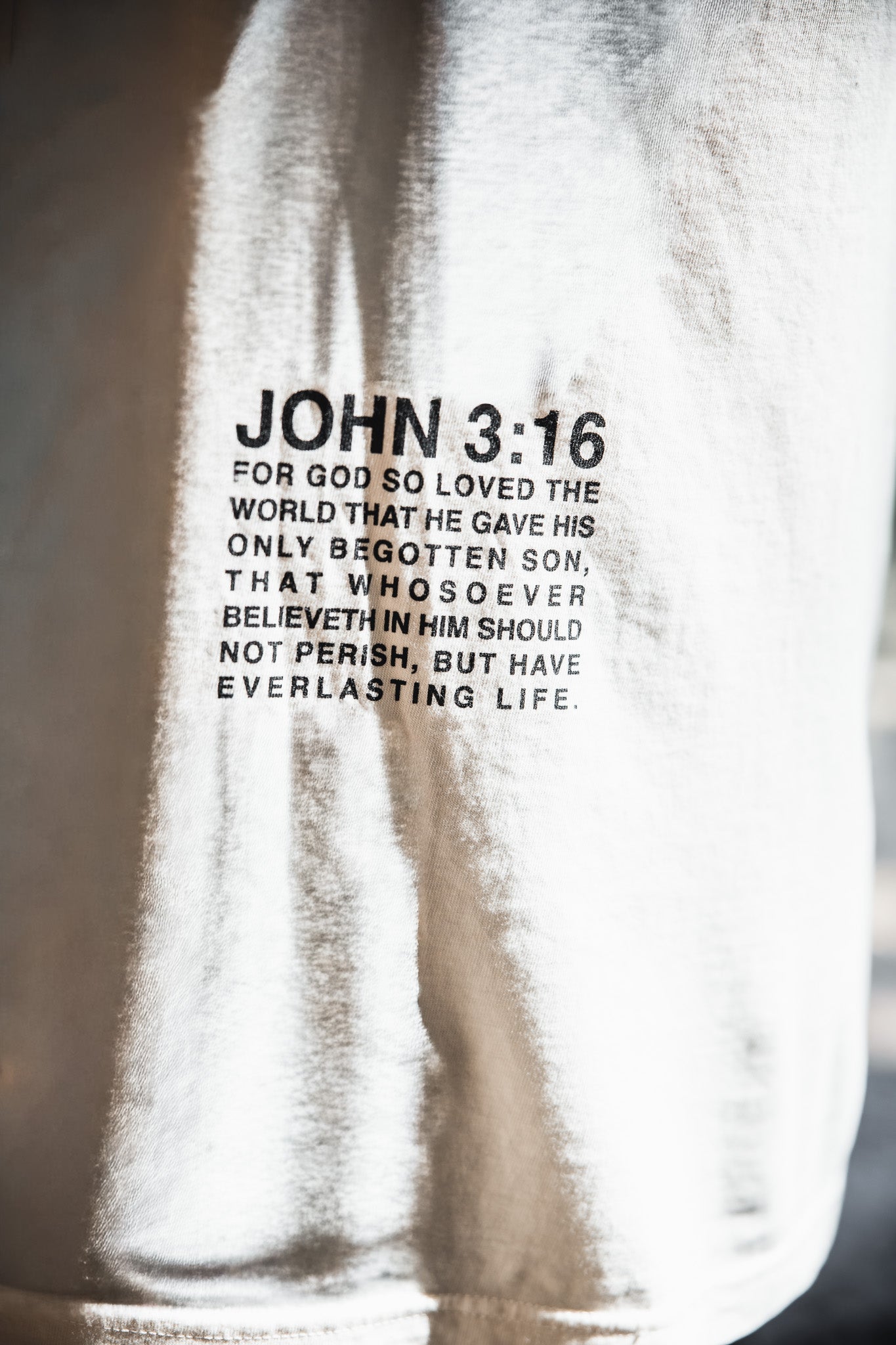 Close-up of the 13th Jesus Saves - White Tee, showcasing John 3:16 in bold black text: "For God so loved the world that he gave his only begotten son, offering everlasting life to all who believe in him.