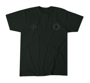 The 13th Victorious Dawn Premium Tee is a black shirt with a small vertical 13TH sword graphic (spiritual strength) on the left chest and a circular cryptic letter design on the right, shown laid flat on a white background.