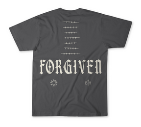 The Forgiven Premium Tee by 13th features "FORGIVEN" in bold Gothic font on the back, a barbed wire graphic above, and small symbols below—including a circular design, "13TH" initials, and subtle references to overcoming addiction or lying.