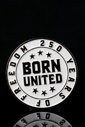 A round pin from Born United Patriot Box by Born United Private Label features black and white text: “250 Years of Freedom” around the edge, “Born United” in bold at the center, seven stars, and a black background—ideal for collectors or fans.