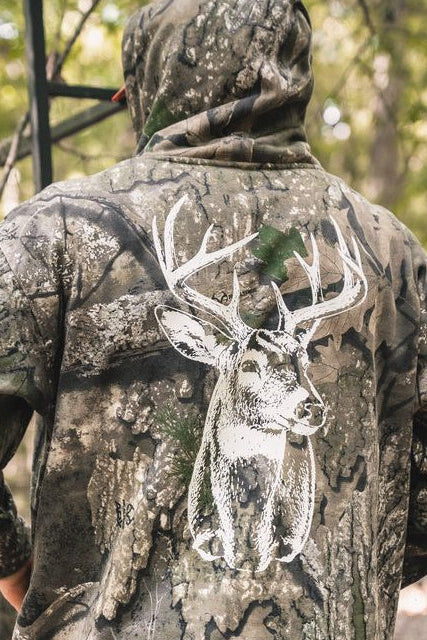 A person wearing The Rut Realtree Premium Hoodie, featuring a large white buck’s head graphic on the back.