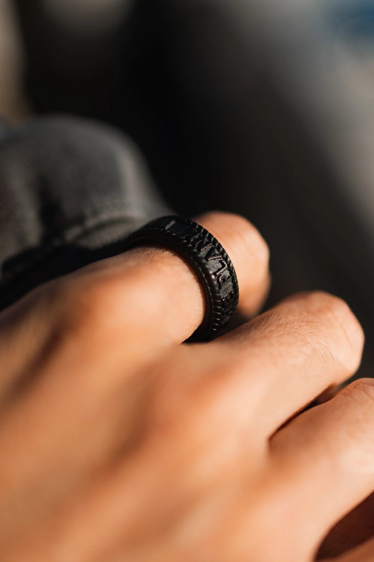 Close-up of a hand adorned with the Walk The Plank - Black Ring by Relentless Betrayal, showcasing its engraved designs against a softly blurred background to highlight the rings details.